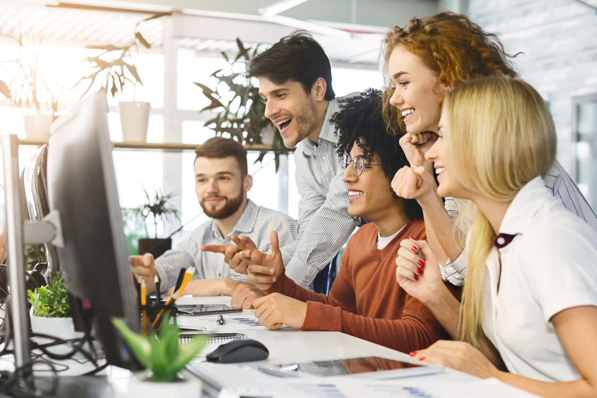 Young team celebrating while looking at computer screen in office together