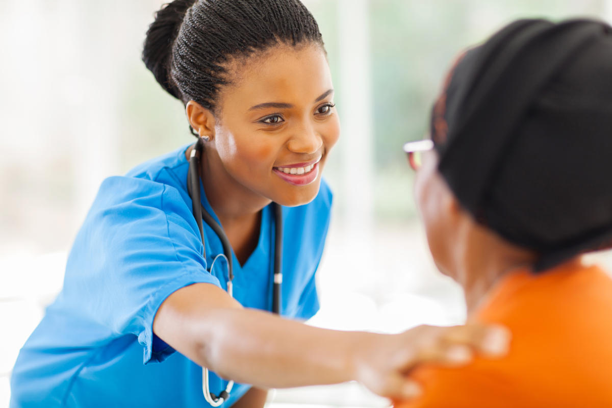 caring medical nurse comforting senior patient in office